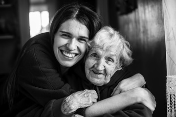 Young woman embracing his elderly mother. Black and white portrait.