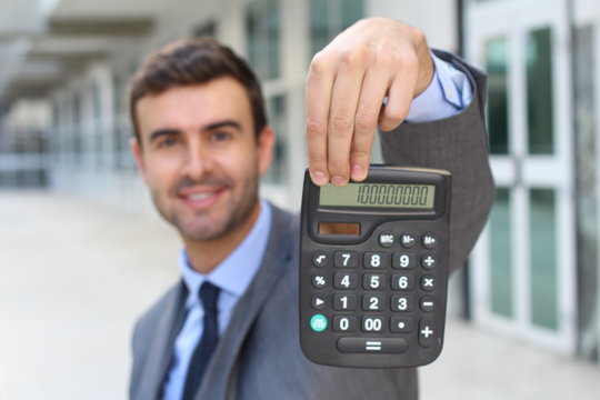 Happy businessman showing a result on his calculator