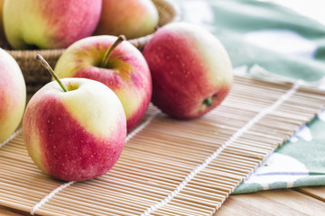 Stack of fuji apple on bamboo mat and in basket put on wood table for background or wallpaper.Delicious sweet and juicy fuji apple suitable for salad cooking or bakery.Fuji apple has origins in Japan.