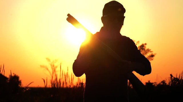 man one hand pumps his shotgun and aim sunset 4k
