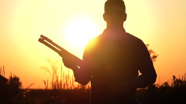 man one hand pumps his shotgun sunset 4k slow motion