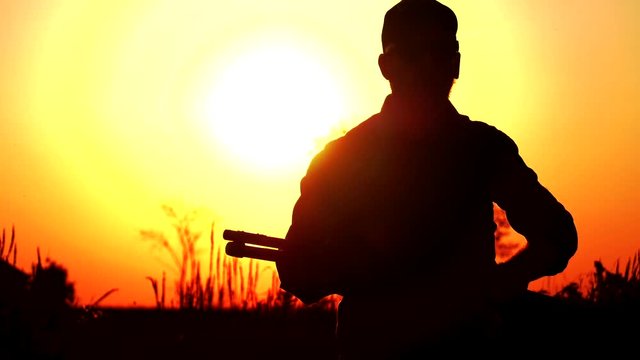 man with shotgun aiming quickly in sunset 4k
