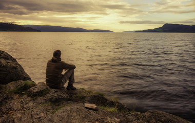 Man Sittting on Sea Shore Watching Sunset