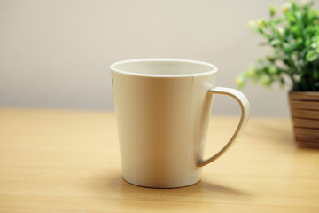 Closeup cup  on wood table and flower pot background.