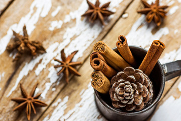 Christmas Baking Ingredients Decoration Cinnamon Sticks Scattered Anise Star Pine Cone in Vintage Jug on Snowy Wood Background. Festive Greeting Card Poster. New Year. Cozy Copy Space
