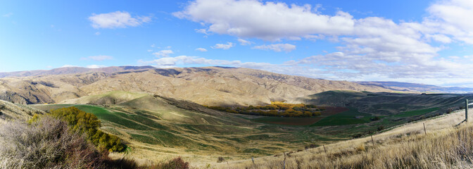 Panoramic image of Lindis Pass Scenic Reserve is the highest point on the South Island's state highway network of New Zealand offering mountain and tussock grassland scenery in Autumn