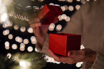 Hand woman open Christmas gift box with bokeh lights background.