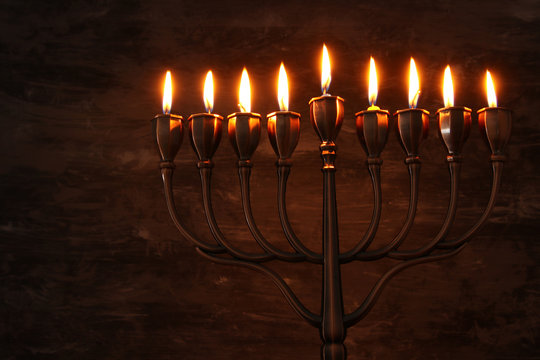 Low key image of jewish holiday Hanukkah background with menorah (traditional candelabra) and burning candles