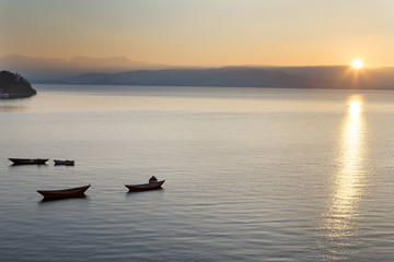 Fototapeta na wymiar Wooden boat on the calm surface of the lake. Chivyrkuisky Bay. The Lake Baikal. Buryatia. Russia.