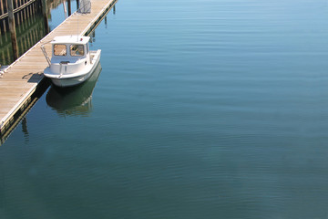 Single, smal boat docked near a wooden pier