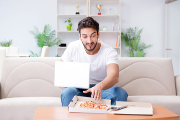 Man eating pizza having a takeaway at home relaxing resting