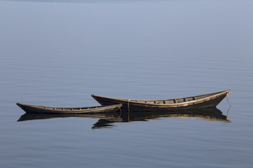 Wooden boat on the calm surface of the lake. Chivyrkuisky Bay. The Lake Baikal. Buryatia. Russia.