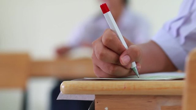Asian students hands holding pencil taking fill drawing selected of choice on Exams paper sheet or test paper on wood desk in school, college with uniform. Education learning concept.