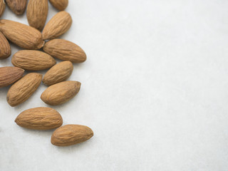 Close-up dried almonds on left side white grey background