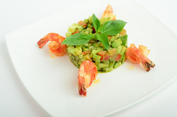 Salad with shrimps, avocado, cherry tomatoes decorated basil on a plate isolated on white background