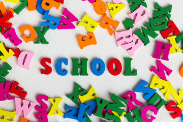 The school among the colored wooden letters on a white wooden background