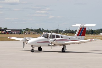 red white and blue dual propeller aircraft stationary on the airport tarmac