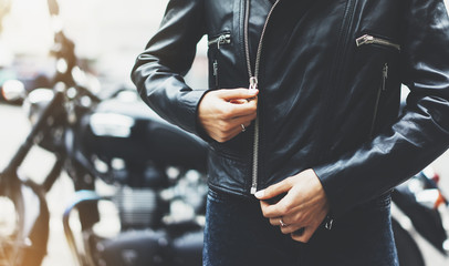 black leather jacket on background motorcycle in sun flare atmospheric city, hipster biker female hands closeup, motorbike street lifestyle, traveler planing bike route in summer holiday concept