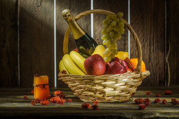 Champagne and fruits in a basket on a wooden background