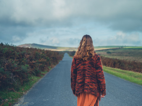 Young woman standing in the road on moor