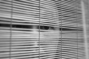 Through wooden blinds the man looks