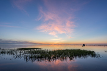 Evening sunlight on coast, pink clouds, blue sky reflection on water. Beach in summer. Seaside natural environment. Shore in Kesselaid, small island in Estonia. Nature Reserve in North Europe