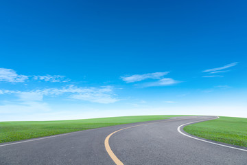 Asphalt road with green grass field scenery blue sky white cloud background.