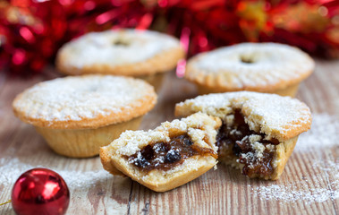 Closeup of an open mince pie on a wooden table with red christmas background - obrazy, fototapety, plakaty