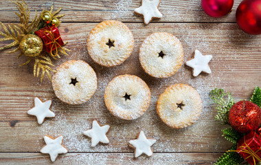 Mince pies and cinnamon stars with christmas decorations on wooden table
