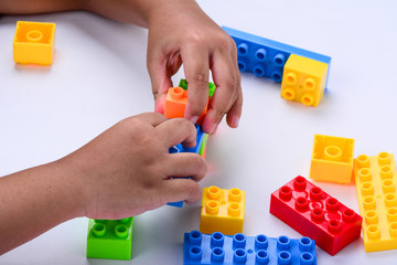A child's hands playing with colourful toy blocks.  White background.