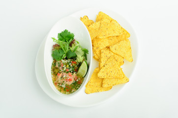 Fresh salmon pickled with vegetables decorated greens and lime with chips on a plate isolated on white background