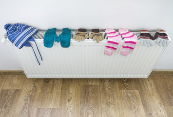 Colored child's socks, gloves and hat drying on radiator. Winter clothes. Selective focus.