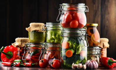 Jars with marinated food and organic raw vegetables