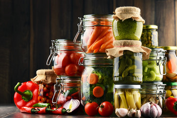Jars with marinated food and organic raw vegetables
