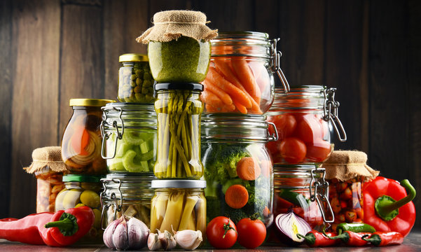 Jars with marinated food and organic raw vegetables