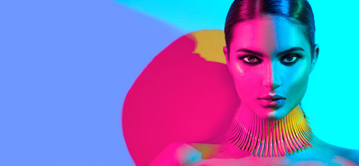 Fashion model woman in colorful bright lights posing. Portrait of beautiful sexy girl with trendy makeup