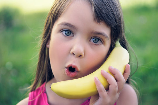 The girl tries to speak by means of a banana instead of phone