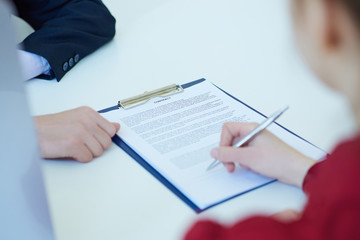 Hands of woman signing the contract. Selective focus on a contract.