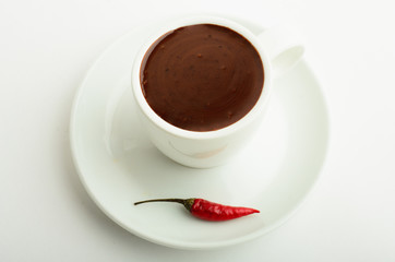 A cup of strong spicy hot coffee witn chile pepper isolated on white background