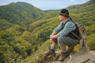 Naklejka premium An old man in the outdoors in the mountains. Senior man on top of the mountain. 