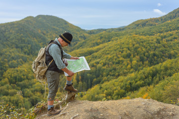The elder man travels to the top of the mountain and reads a map of the route.
An old man tourist in the mountains uses a tourist card.
