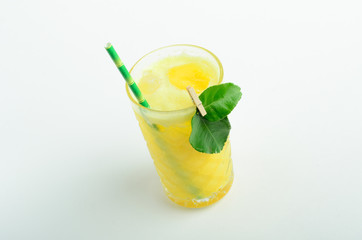 Yellow lemonade with ice decorated leaves in glass isolated on white background