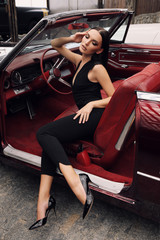 Fototapeta premium beautiful girl with dark hair in elegant clothes posing in luxurious car