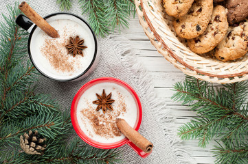 eggnog cocktail in mug arranged with christmas decoration and cookies box on white wooden table