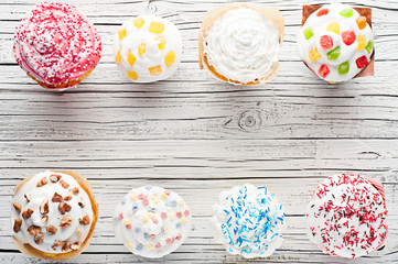 variety of cupcakes on white wooden background top view