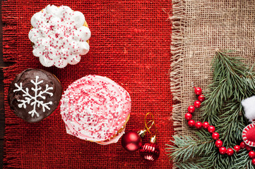 christmas decorated cupcakes at red burlap background top view