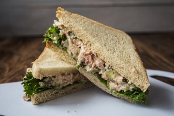 tuna pickles sandwich with salad on white plate