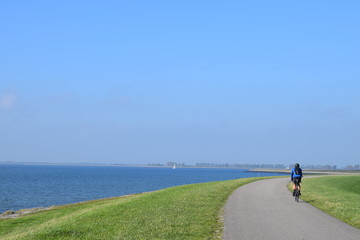 Typical dutch image of people cycling on the dike
