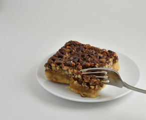 Fork taking first bite of a sweet Pecan Bar dessert