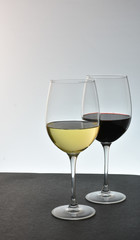 Two staggered glasses of wine with white wine in front of red